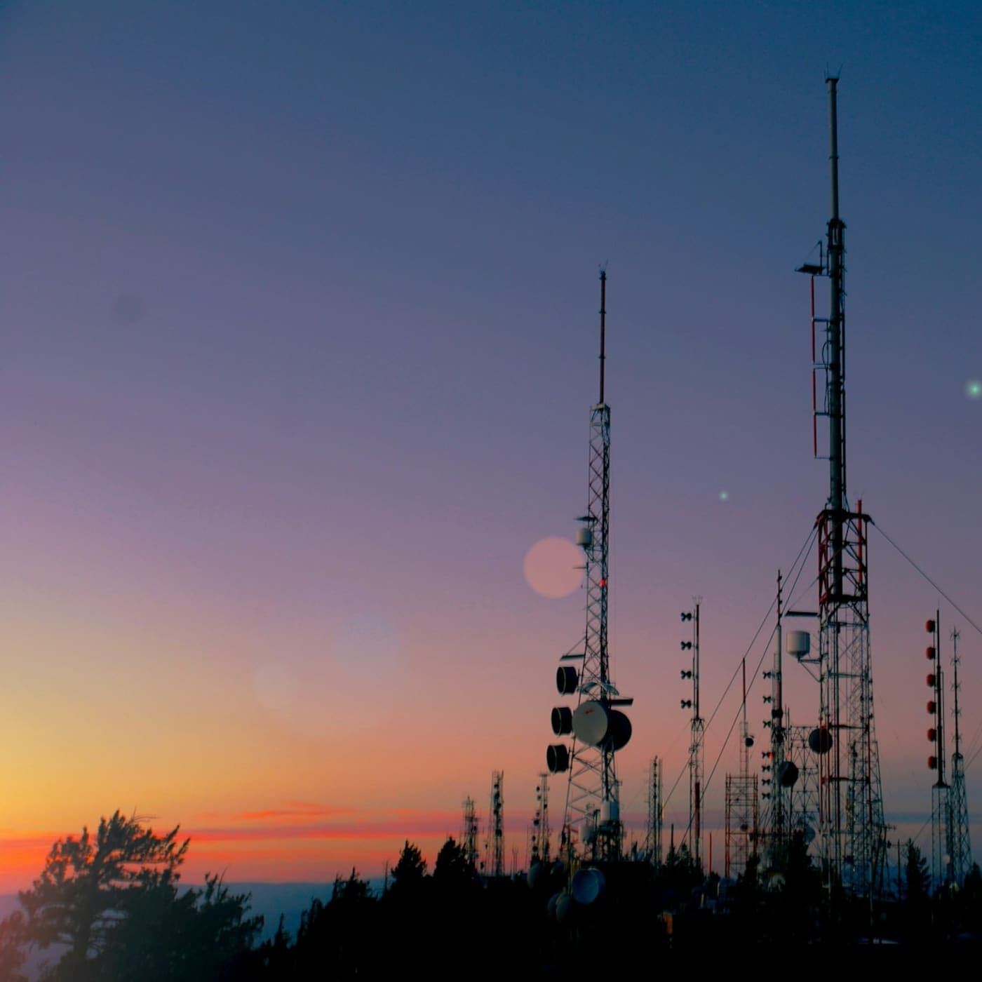 Antenna masts silhouetted against a sunset