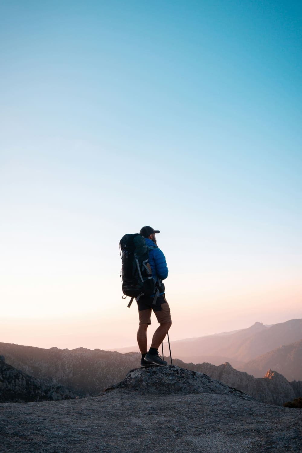 Hiker with a pack looking over mountains at sunset